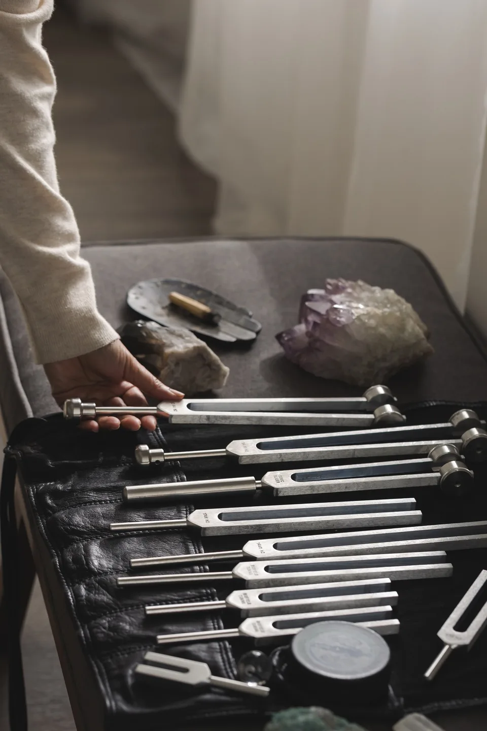 A hand choosing a fork from a full kit laid out beside crystals