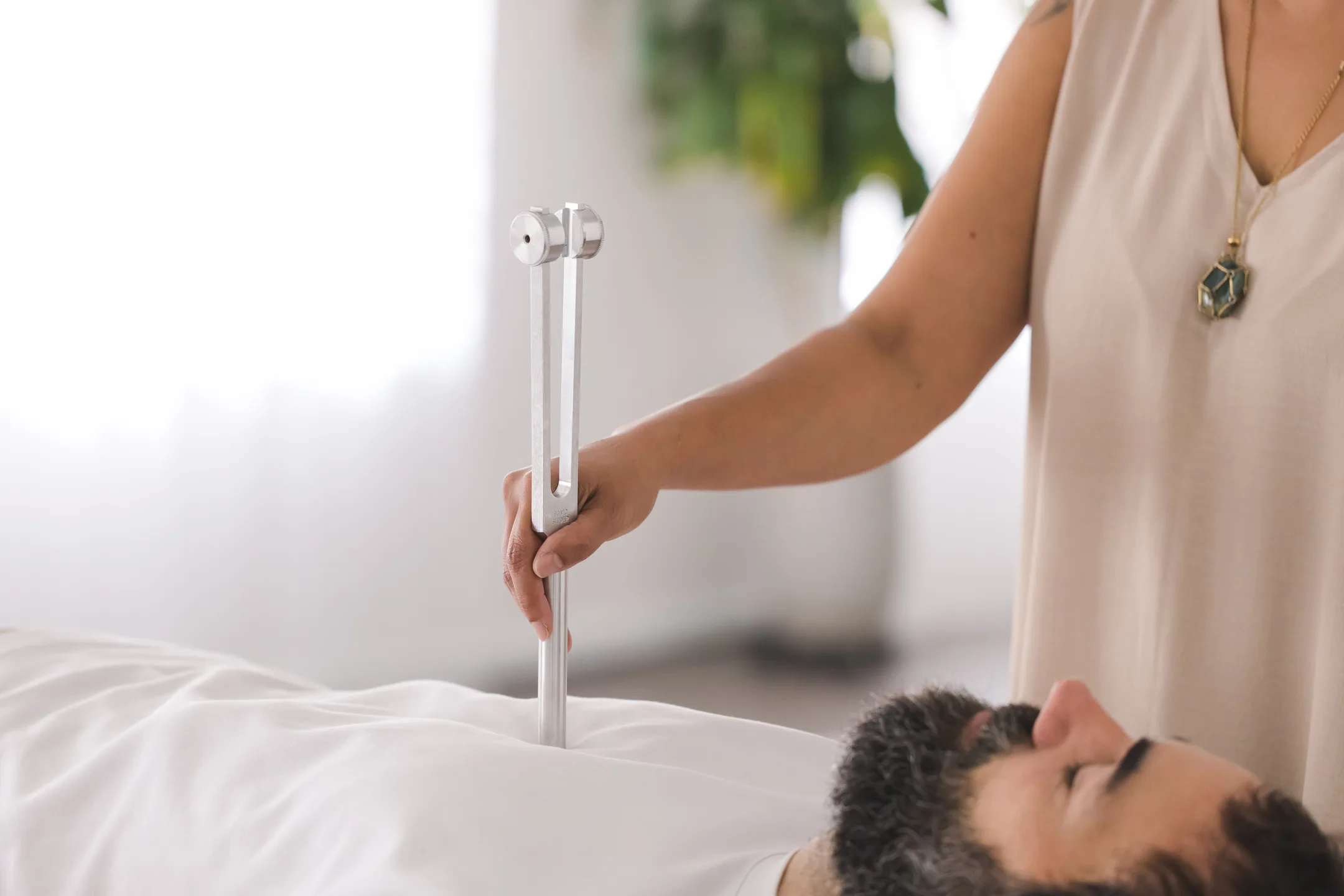 Close-up of a calibrated tuning fork held near a client during a biofield tuning session